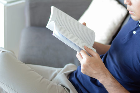 A man reading book while sitting on the couch