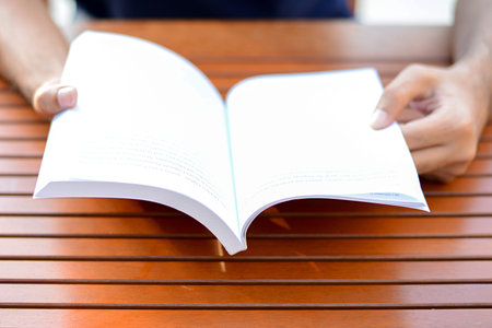 Hand opening book on the table - reading concept