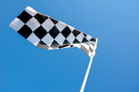 Checkered flag flying on blue sky backgroundの写真素材