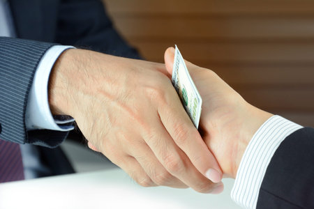 Handshake of businessmen with money - bribery concept
