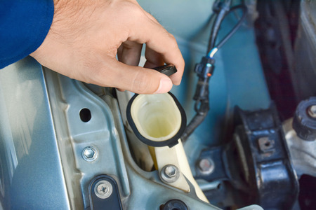 Hand opening car windscreen washer tank checking water level - hand focusedの写真素材
