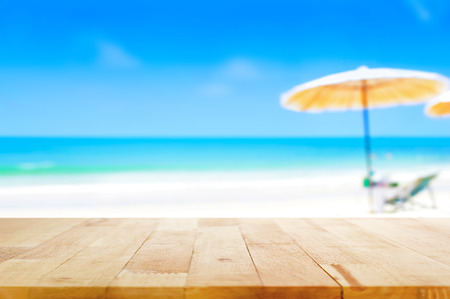 Wood table top on blurred blue sea and white sand beach background - can be used for display or montage your productsの写真素材