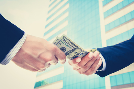 Hands of businessmen passing money, US dollar bills - vintage toneの写真素材