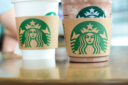 Starbucks coffee cup and chocolate frappe on the table in Starbucks coffee shop. Starbucks brand is worldwide coffeehouse chains from USA.のeditorial素材