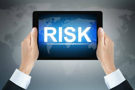 RISK sign on tablet pc screen held by businessman handsの写真素材