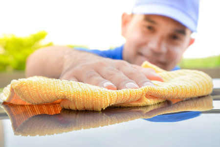 A man polishing car with microfiber cloth, car detailing (or valeting) concept