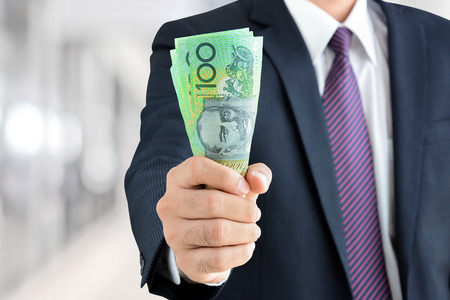 Businessman hand holding money, Australian dollar (AUD) banknotes - financial, investment success and profitable business conceptsの写真素材