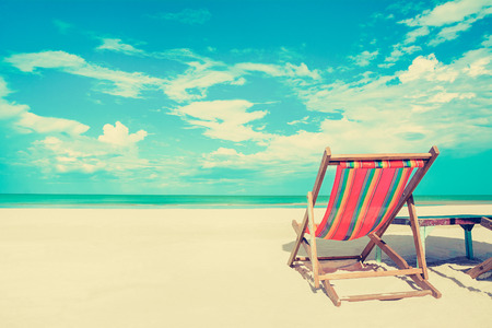 Beach chair on white sand beach in sunny sky background, vintage tone - summer holiday concept