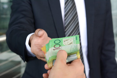 Businessman hands passing money, Australian dollar (AUD) banknotes