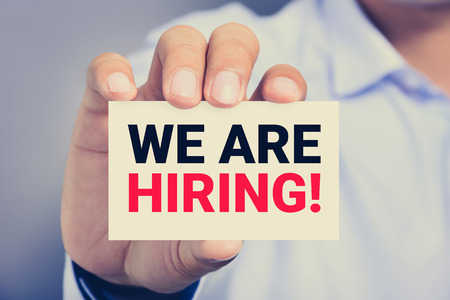 WE ARE HIRING!, message on the card shown by a man, vintage tone WE ARE HIRING!, message on the card shown by a man, vintage tone