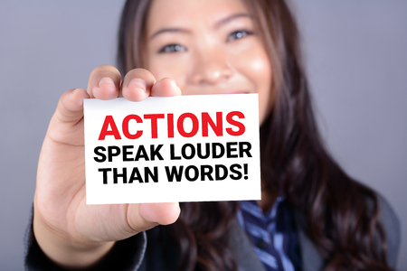 ACTIONS SPEAK LOUDER THAN WORDS, message on the card shown by a woman ACTIONS SPEAK LOUDER THAN WORDS, message on the card shown by a woman