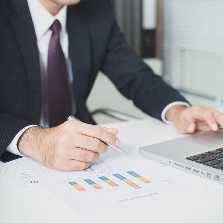 Businessman working with laptop computer and documents on the table - hand focused, soft tone