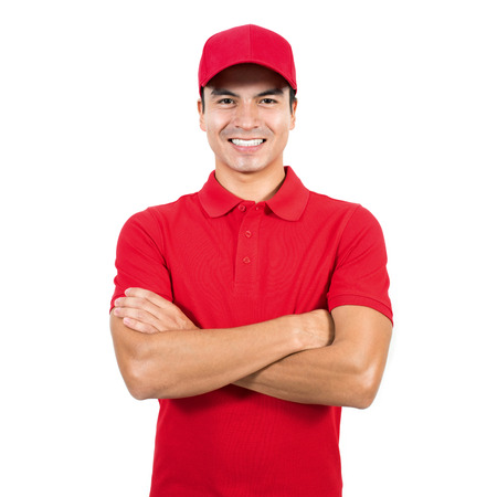 Smiling delivery man in red uniform standing with arm crossed - isolated on white backgroundの写真素材