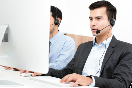 Businessmen wearing microphone headset in call center as the operators, telemarketers or customer service staffs etc.の写真素材