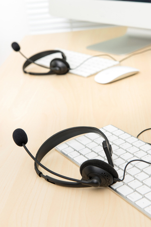 Microphone headsets on the table with computer keyboards in call center, selective focusの写真素材