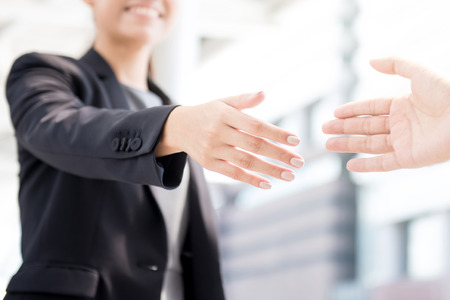 Businesswoman going to make handshake with a businessman -greeting, dealing, merger and acquisition conceptsの写真素材