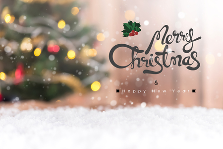 Merry Christmas and Happy New Year text on blur decorated Christmas tree in the snowの写真素材