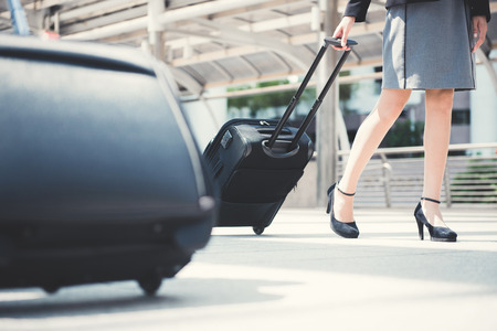 Businesswoman (lower part) walking and pulling luggage - business traveling conceptの写真素材