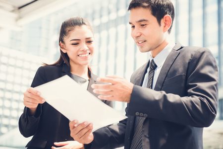 Asian businesswoman and businessman  discussing document outdoor