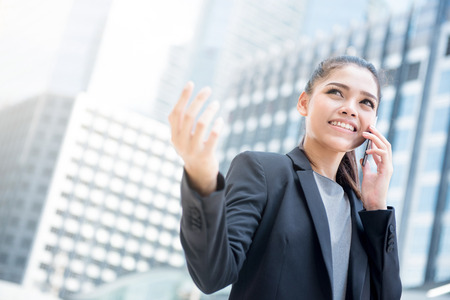 Young Asian businesswoman talking on smartphone with hand gestureの写真素材