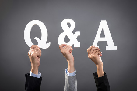 Businesspeople raising their hands with letters showing Q & A signの写真素材