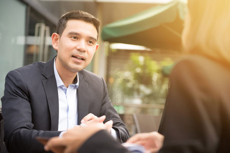 Asian businessman talking with a businesswoman in outdoor cafeの写真素材