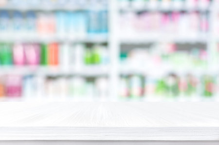 Empty wood counter top on blur pharmacy shelf (or chemist and cosmetic shop) backgroundの写真素材
