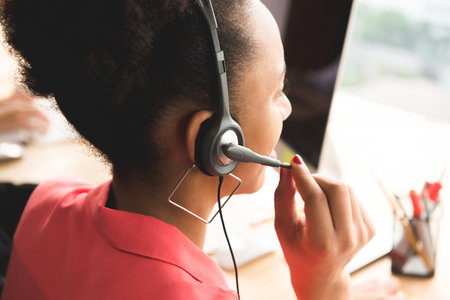 Back view of black businesswoman wearing microphone headset working in the officeの写真素材