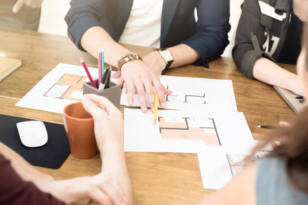 Group of architects (or interior designers) discussing floor plans in the meeting