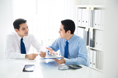 Asian businessmen discussing financial documents at meeting table in the officeの写真素材