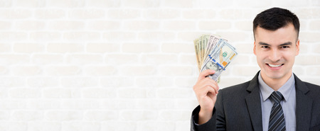 Young smiling businessman showing US dollar money, banner with copy spaceの写真素材