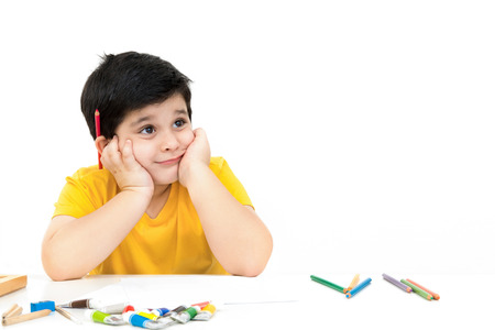 Cute little boy thinking of what to draw and paint - learning, education and imagination conceptsの写真素材