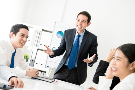 Happy cheerful businessman as a meeting leader talking to his colleagues in the meetingの写真素材