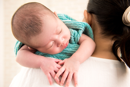 Mother carrying sleeping adorable little baby over shoulderの写真素材