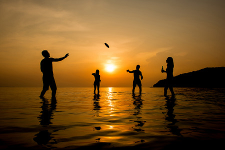 Silhouette of people playing at the beach in summer sunsetの写真素材