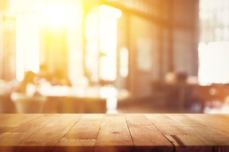 Wood table top on blur restaurant (cafe) interior background with sunlight - can be used for display or montage your products (foods)の写真素材