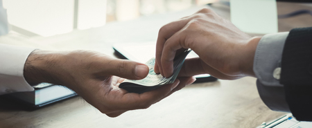 Hand of a businessman giving money to his partner, bribery and corruption concepts - panoramic bannerの写真素材