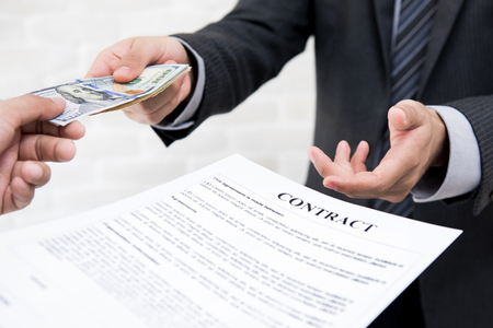 Businessman giving money together with contract - debt, loan and bribery conceptsの写真素材