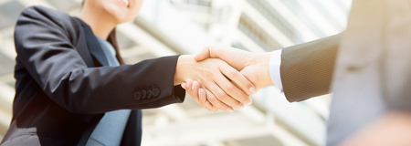 Businesswoman making handshake with a businessman, female leader concept - panoramic web bannerの写真素材