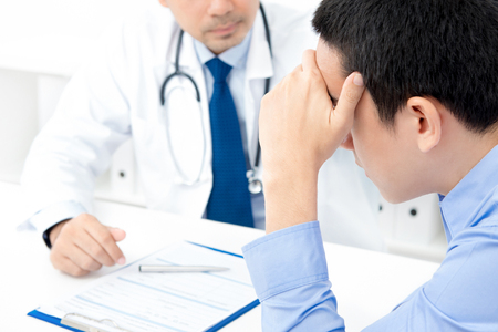 Young stressed male patient consulting with doctorの写真素材