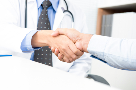 Doctor making handshake with patient in the officeの写真素材