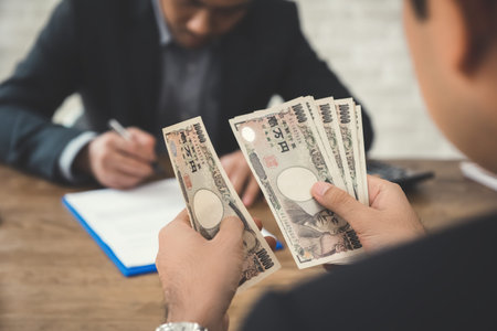 Businessman counting money, Japanese yen banknotes, while making agreement with partnerの写真素材