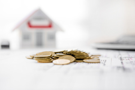 Money on blueprint paper with blurred house model in background - real estate loan and financial conceptsの写真素材