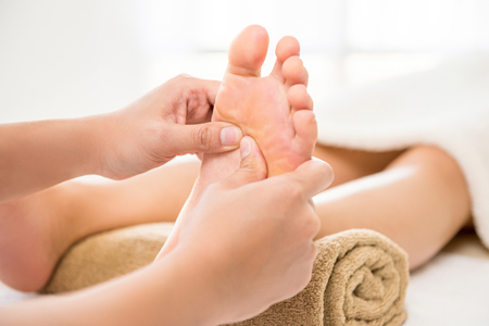 Professional therapist giving traditional thai foot massage to a woman in spaの写真素材
