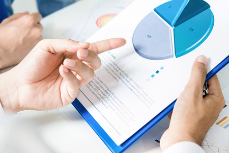 Hand of businessman pointing to pie chart on paper - data analysis conceptの写真素材