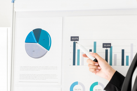 Hand of businesswoman holding marker pointing on graph data while making a presentationの写真素材