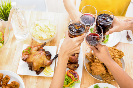Group of friends clinking glasses, cheers, at dinning table in the partyの写真素材