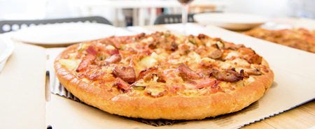 Chicken pizza on unfolded box at dinning table - panoramic bannerの写真素材