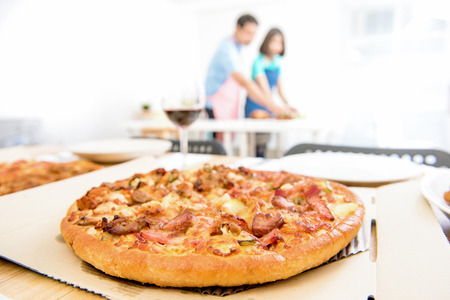 Chicken pizza on unfolded box at dinning table in the houseの写真素材