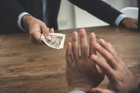 A man refusing money, Japanese yen, from a busisnessman - anti bribery and corruption conceptsの写真素材